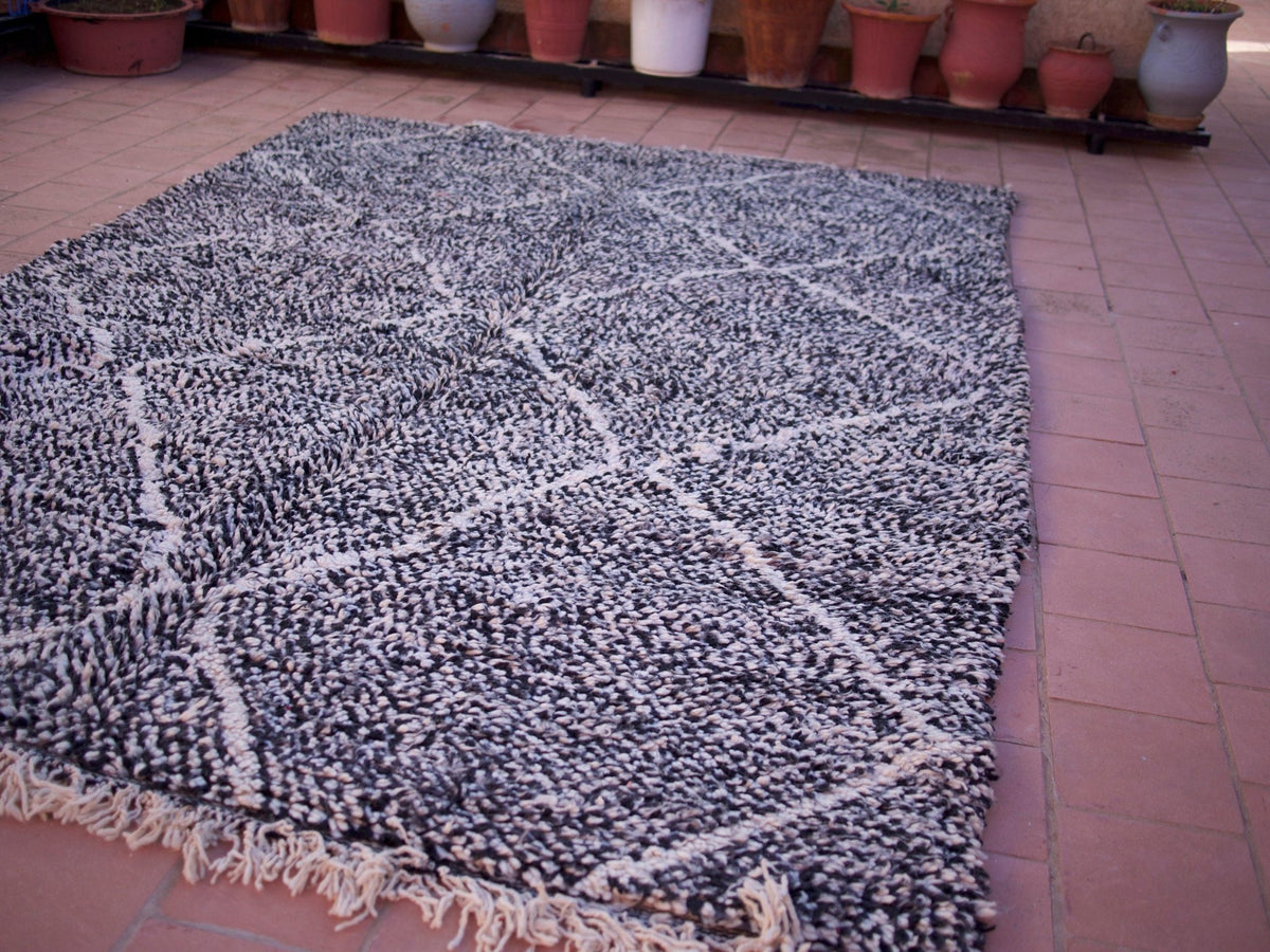 Detail shot highlighting the fringe edges of the black Moroccan Beni Ourain rug with geometric designs.
