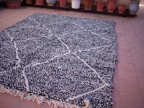 Detail shot highlighting the fringe edges of the black Moroccan Beni Ourain rug with geometric designs.