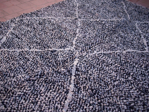 Close-up detail of the textured surface of the black Beni Ourain rug featuring geometric patterns.