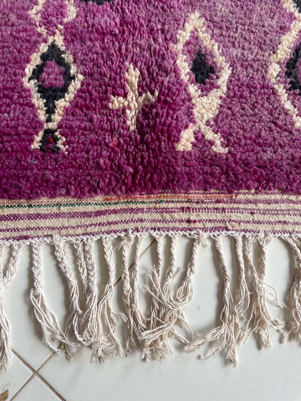 Detail view of the vintage wool rug featuring geometric patterns and fringe detail.