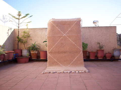 Lifestyle shot of a brown Beni Ourain Moroccan rug on a natural background.