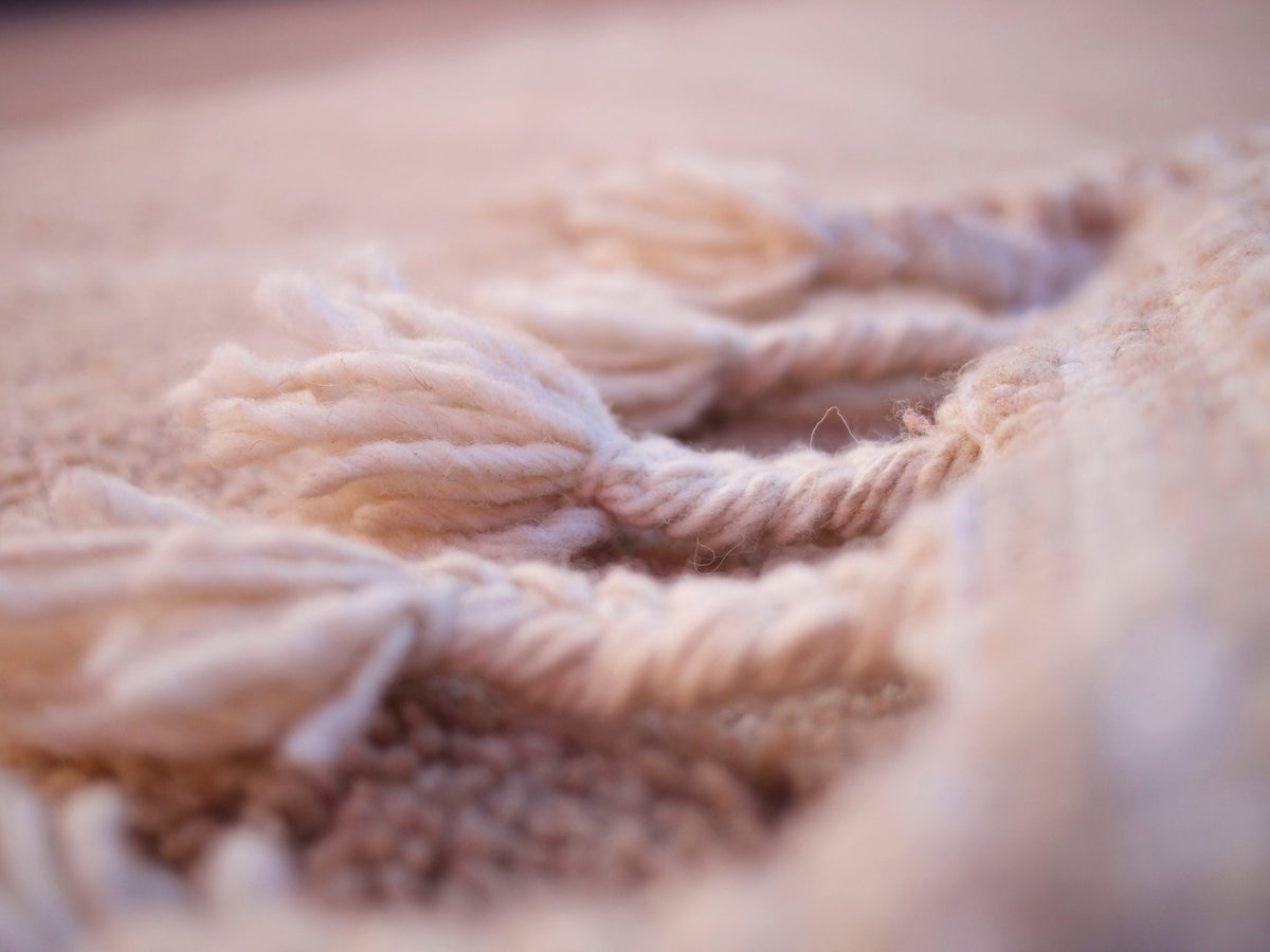 Close-up detail showing the soft texture and fringe details of the brown rug.