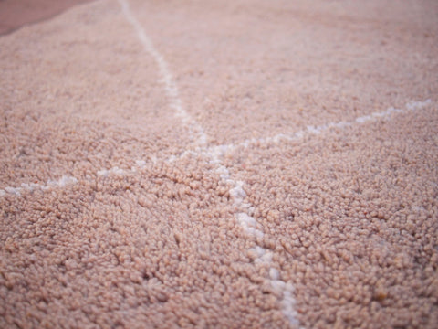 Detail close-up of the patterned design on the textured surface of the brown rug.