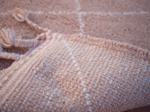 Detail shot of the woven texture and fringe edges of the brown handmade rug.