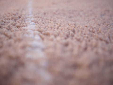 Detail close-up showcasing the textured surface of the brown Berber rug.