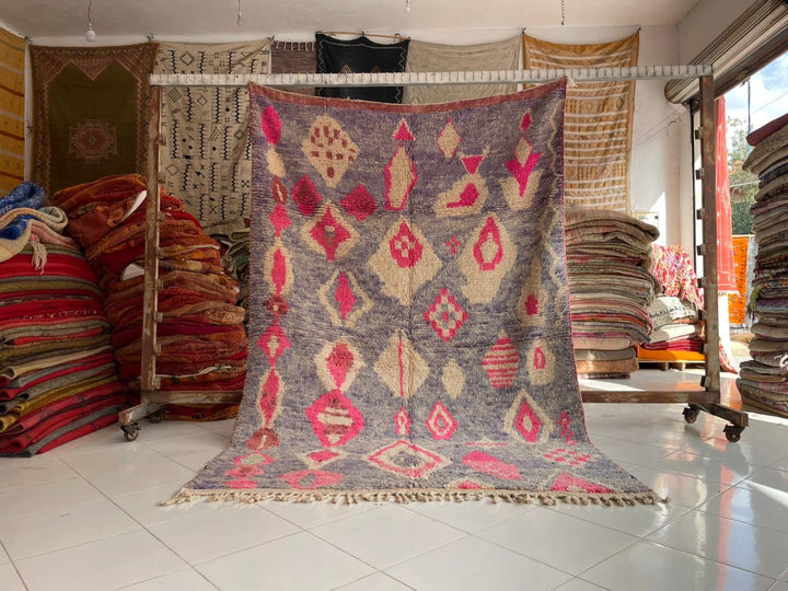 Lifestyle shot of the faded pink Moroccan rug with geometric patterns in a natural setting.