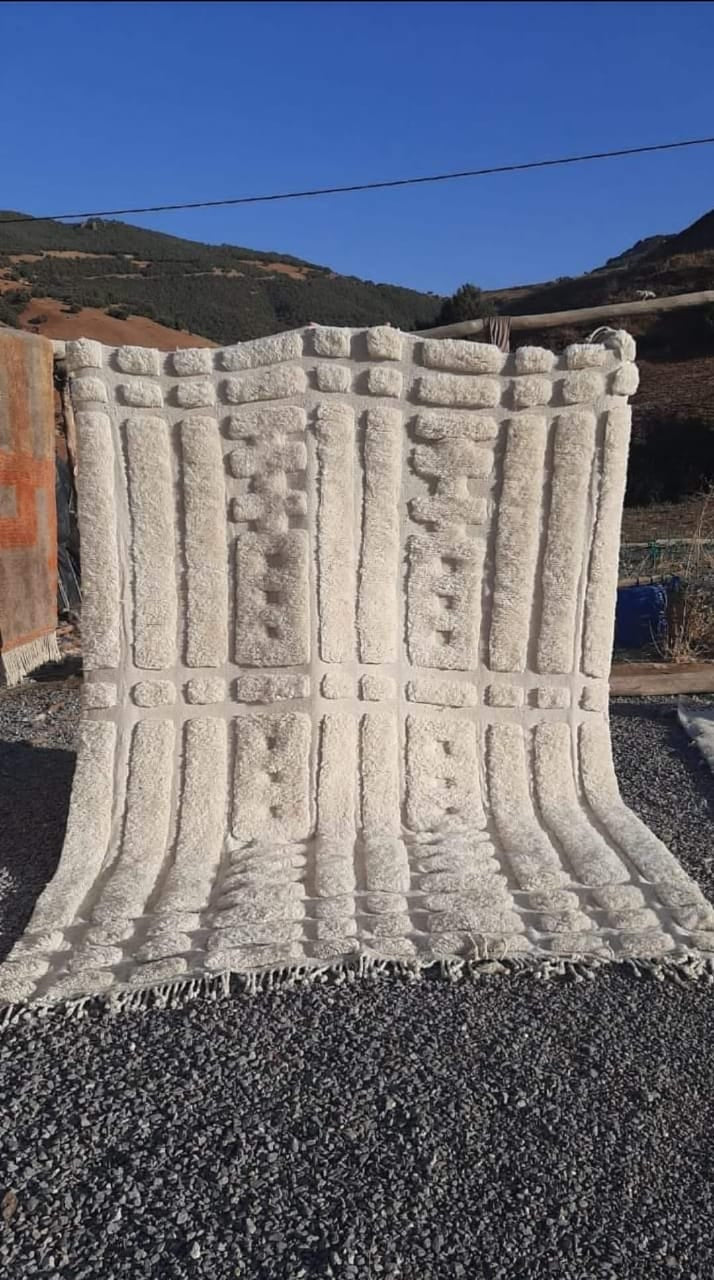 Lifestyle shot of a white tufted Moroccan Mrirt rug with a soft texture in a natural setting