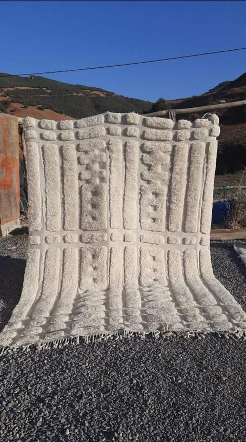 Lifestyle shot of a white tufted Moroccan Mrirt rug with a soft texture in a natural setting