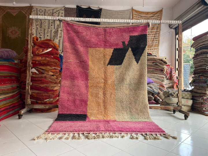 Lifestyle shot of a pink Berber rug with geometric patterns and fringe edges.