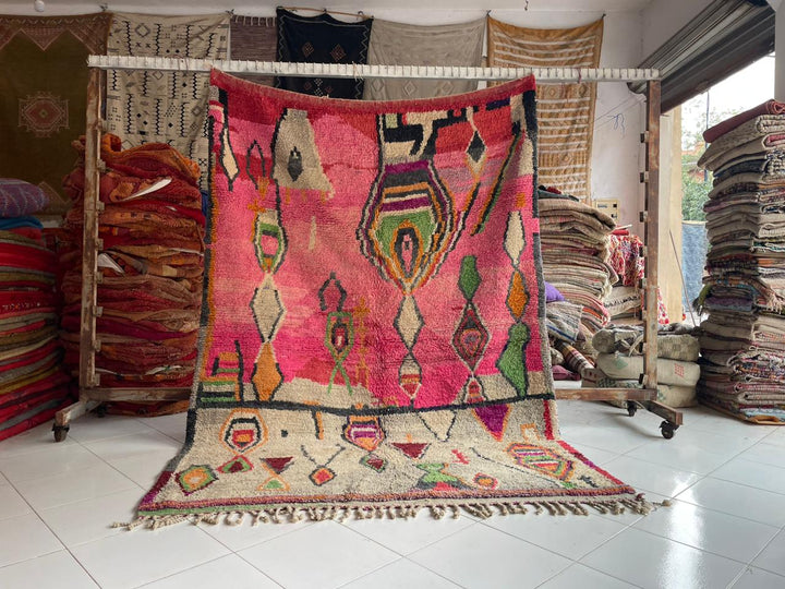 Lifestyle shot of a pink Berber rug with geometric patterns in a natural setting.