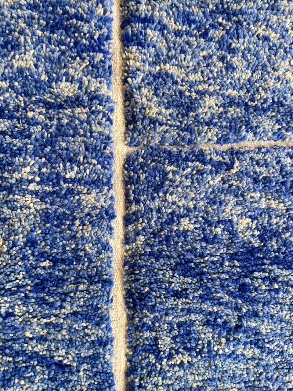 Front view of a large blue Moroccan rug featuring fringe edges and a geometric design.