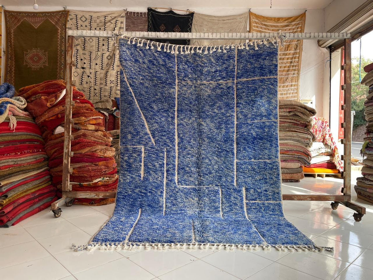 Lifestyle shot of a blue Moroccan rug with a patterned design in a studio setting.