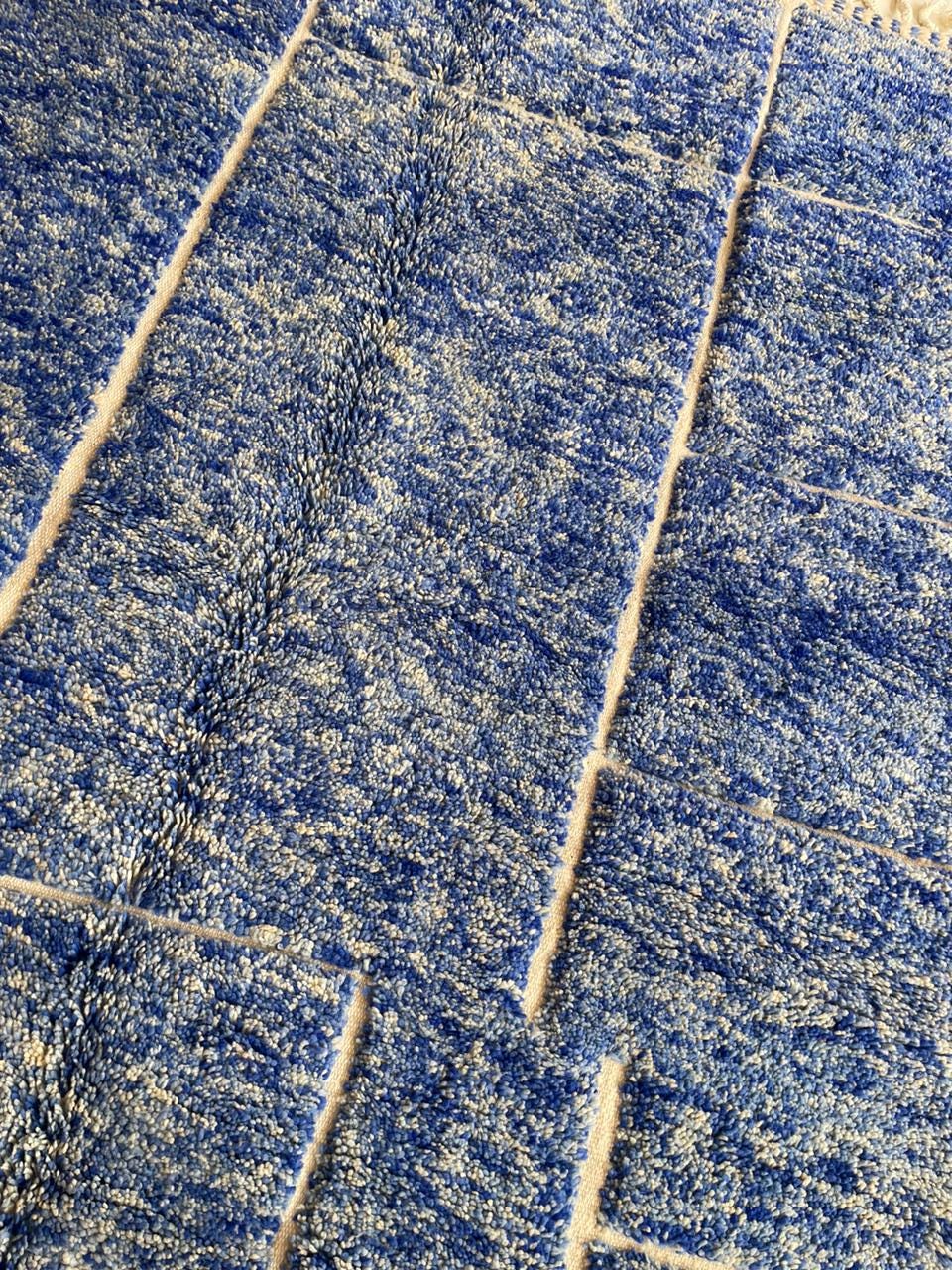 Detail shot of a blue Moroccan rug with a textured pattern in a neutral background.