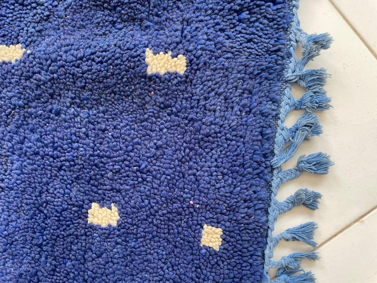 Close-up detail of the fringe on a blue Moroccan rug.