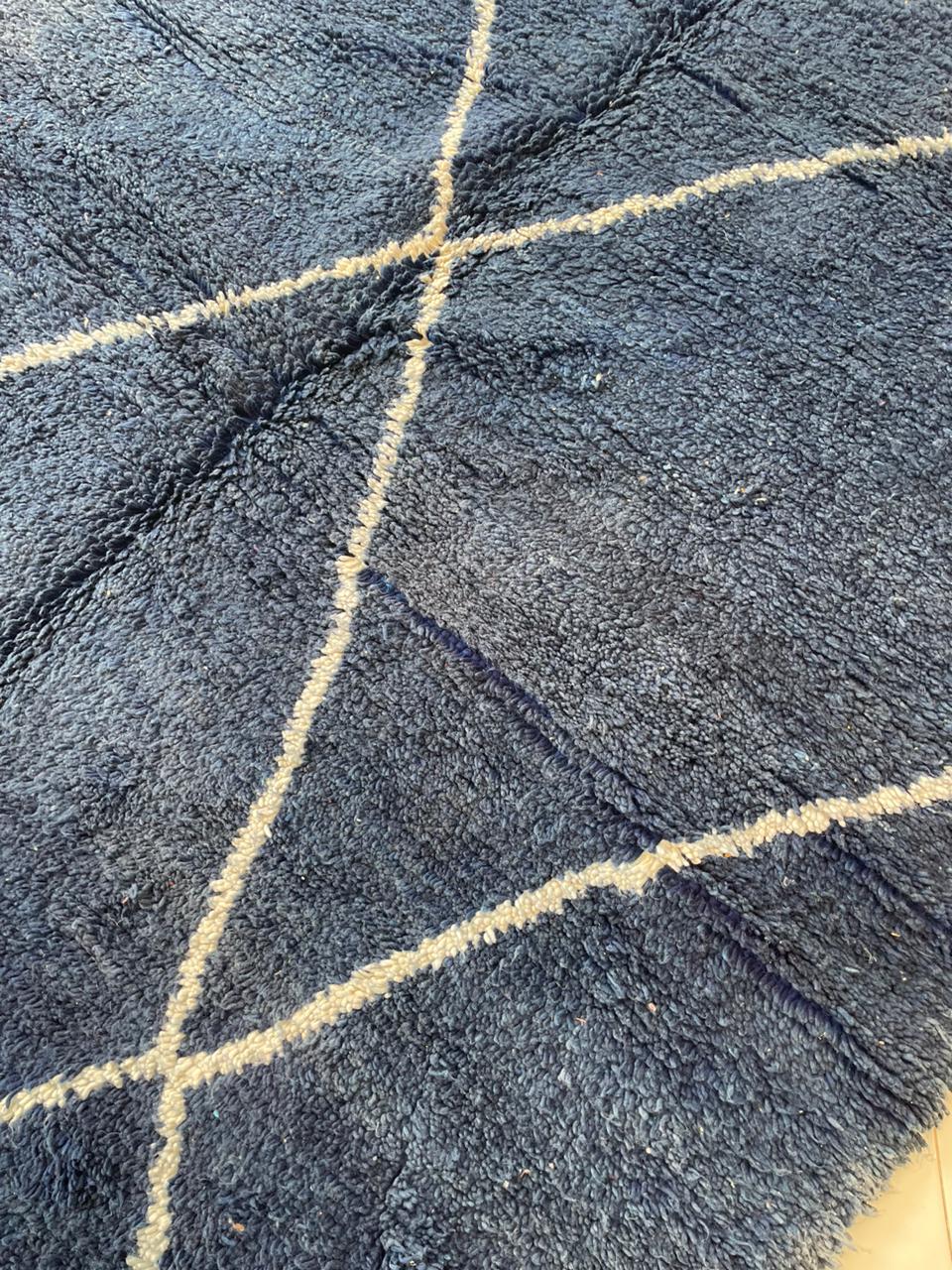 Close-up detail of a blue Moroccan rug showcasing a geometric pattern and soft texture.