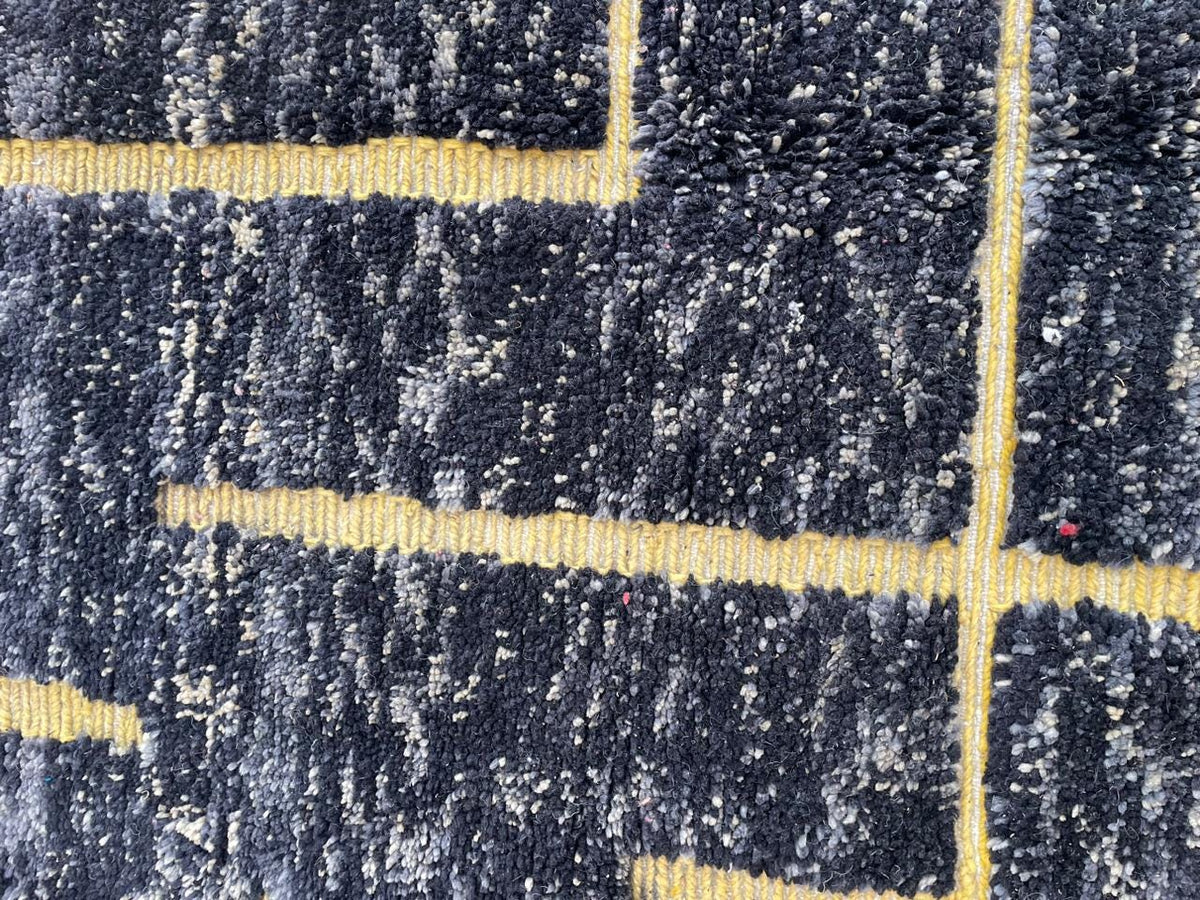 Close-up detail of the textured surface and geometric pattern of the black and yellow rug.