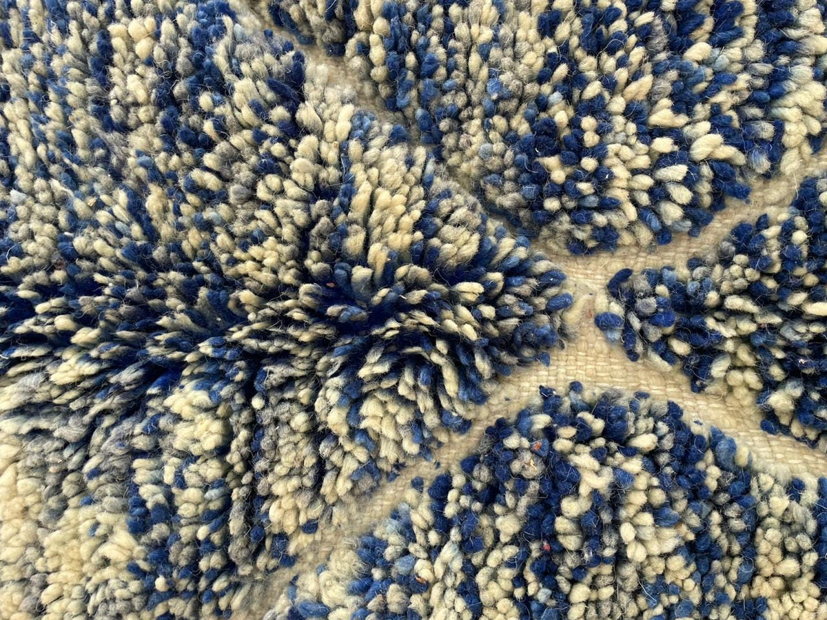 Detail view of a blue and black rug showcasing a floral pattern.
