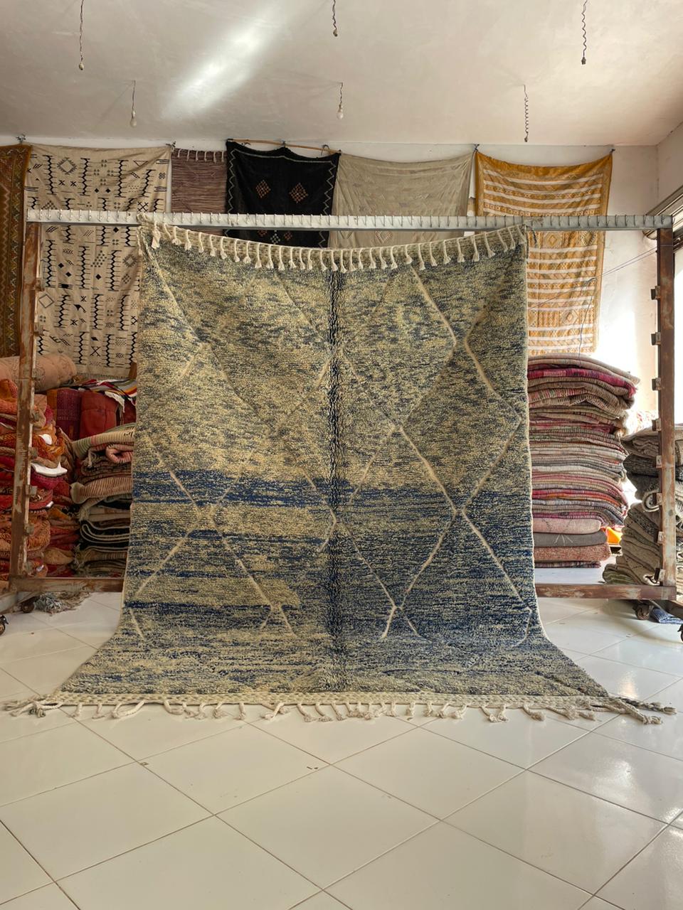 Lifestyle shot of a blue and black Moroccan rug with fringe edges on a natural background.
