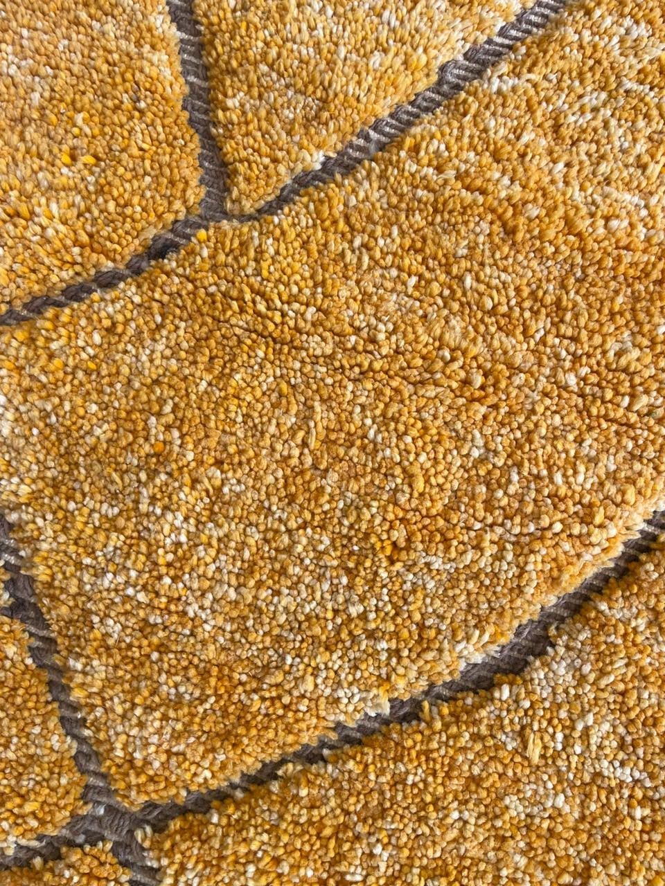 Detail close-up of a yellow rug with a textured surface and geometric design.