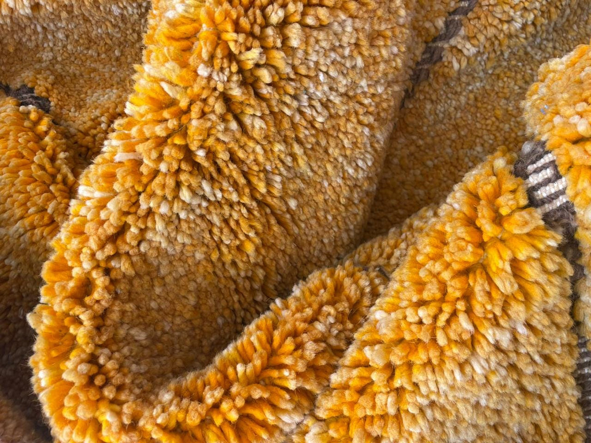 Detail close-up of a yellow textured rug emphasizing its handmade appearance.
