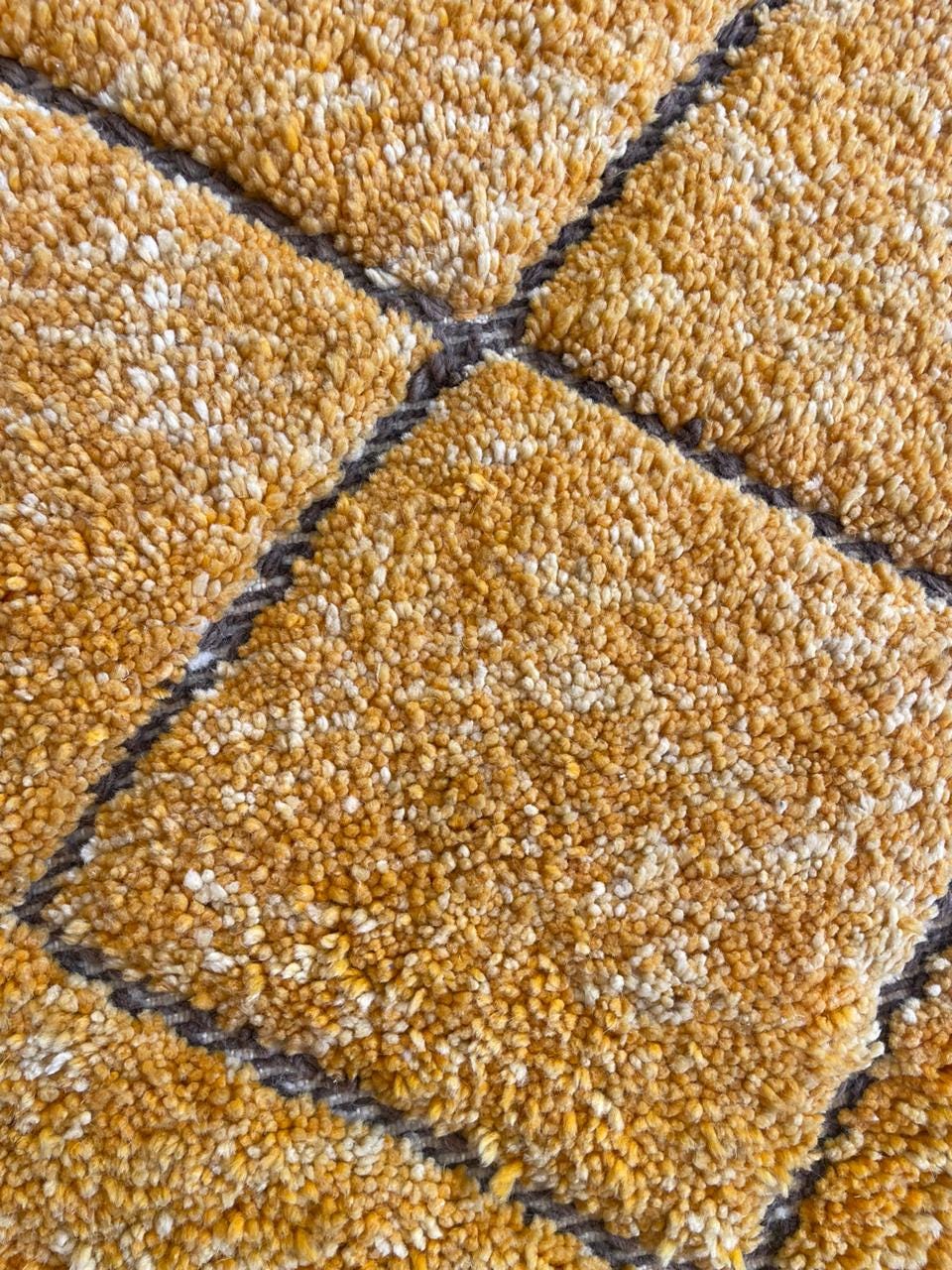 Detail close-up of a yellow patterned rug featuring geometric designs.