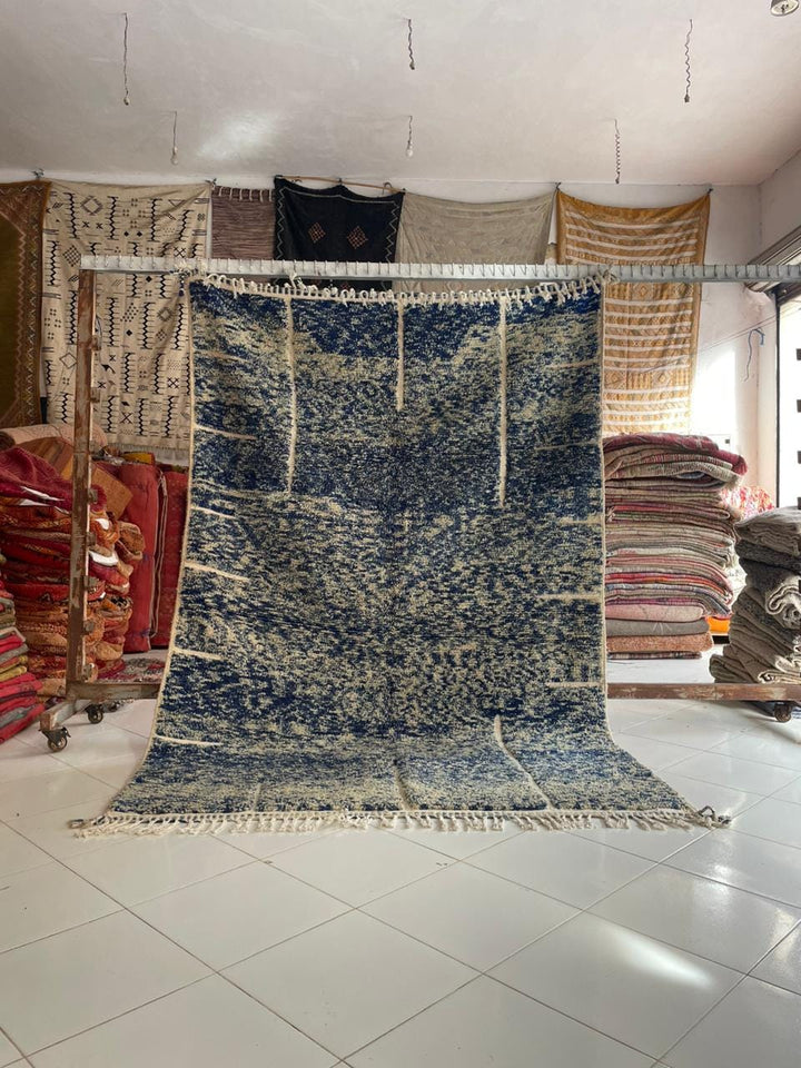 Lifestyle shot of a blue Moroccan rug with geometric patterns in a natural setting.
