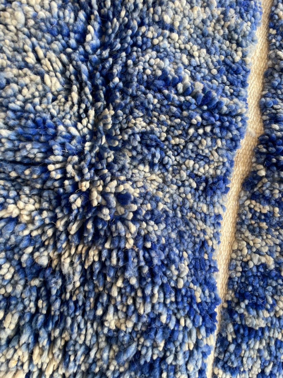 Detail close-up showing the soft texture of the blue Moroccan rug.