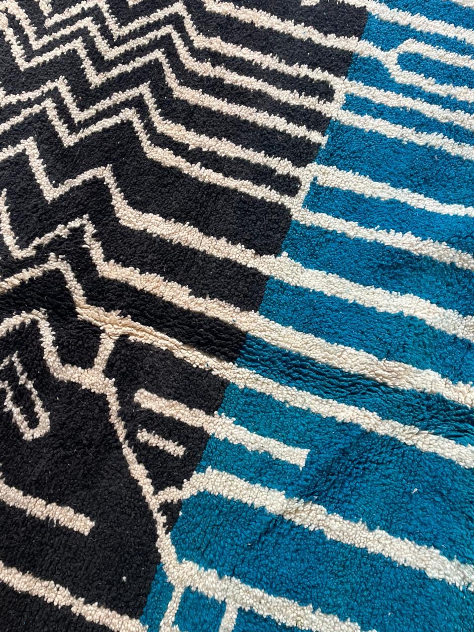 Side view of a blue Moroccan rug showcasing geometric patterns on a white background.