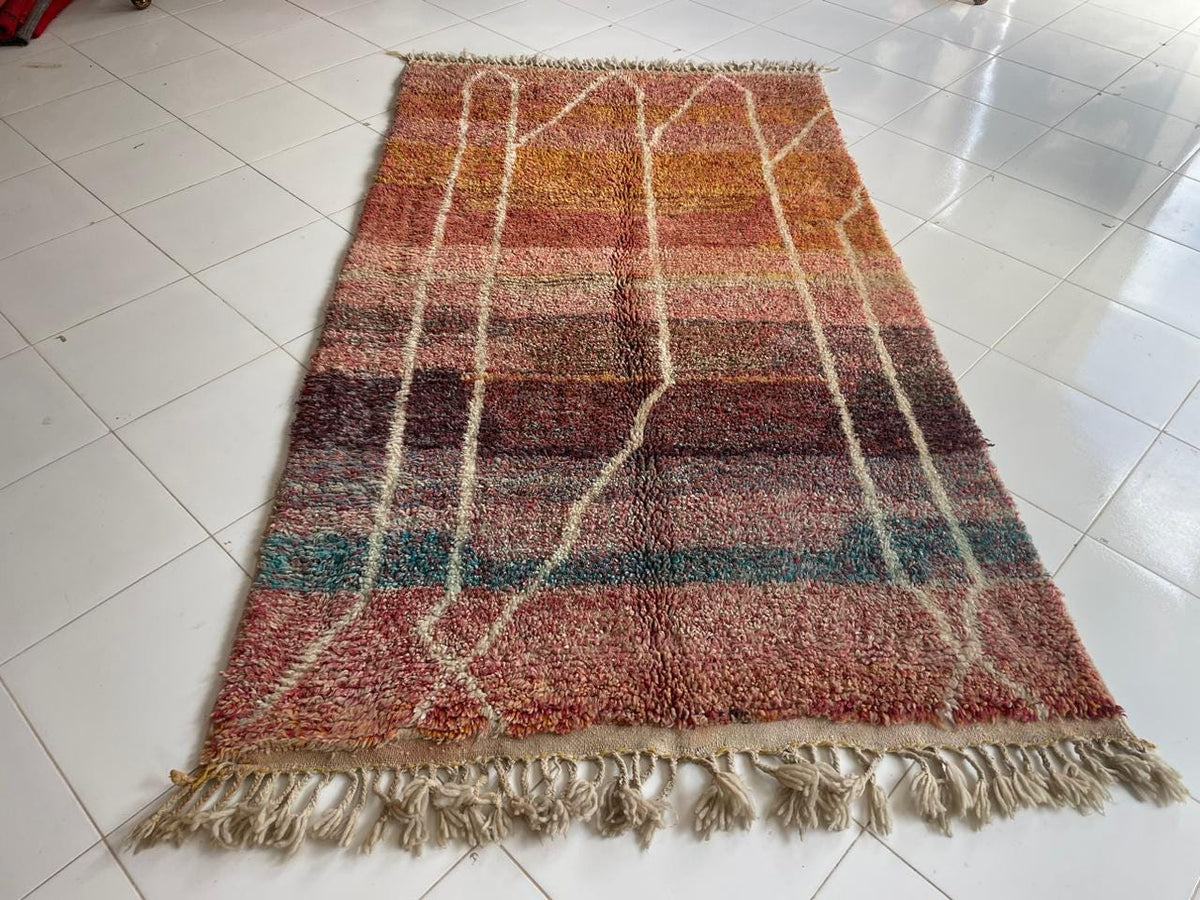 Detail close-up of a brown Moroccan rug featuring fringed edges and geometric patterns.