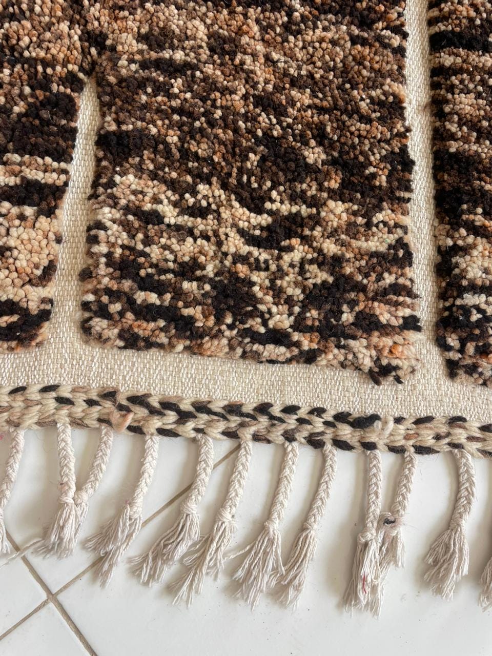 Close-up detail of a brown Moroccan rug featuring a textured pattern against a contrasting background.