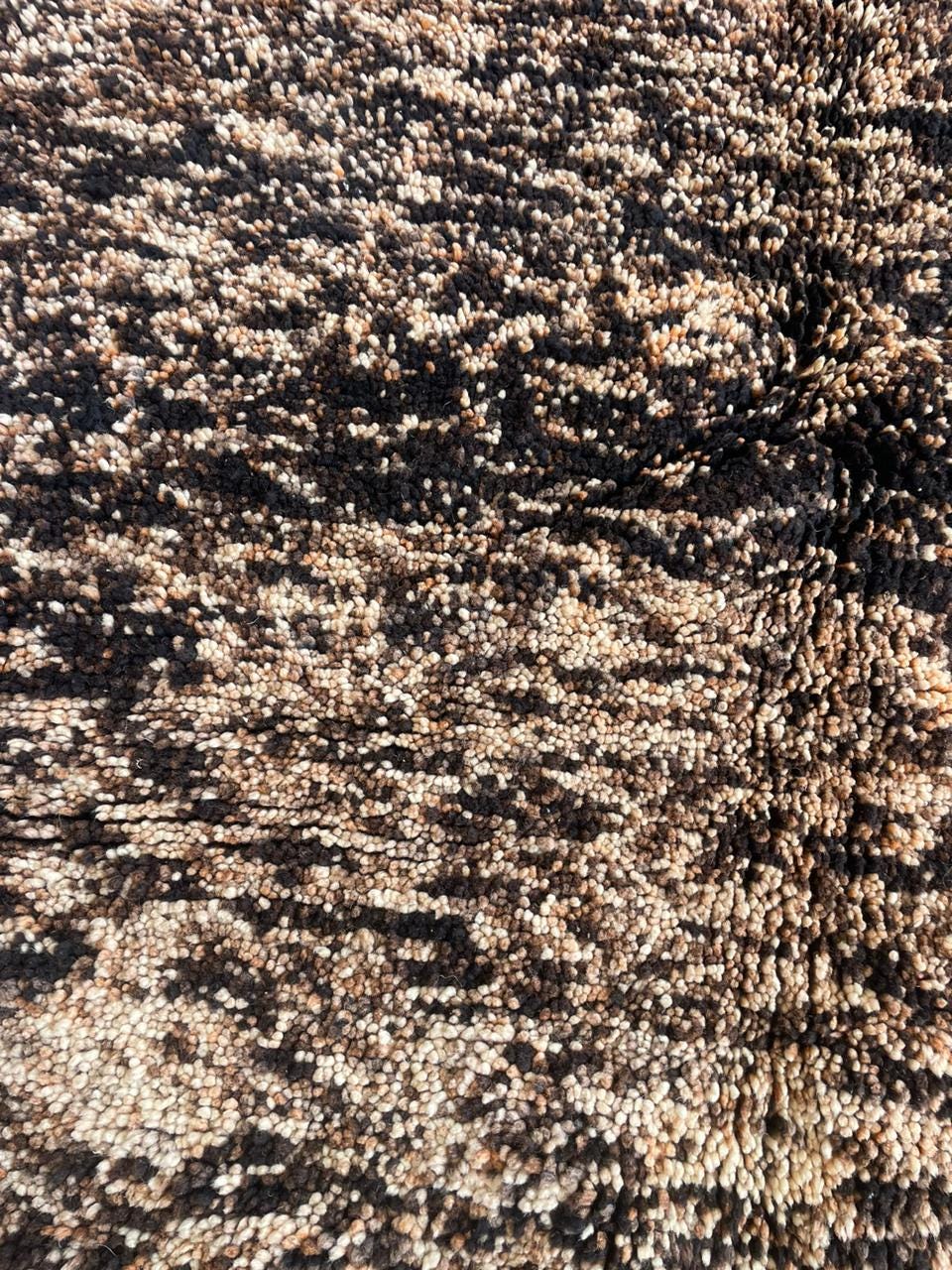 Close-up of a brown Moroccan rug showcasing a textured pattern against a contrasting background.