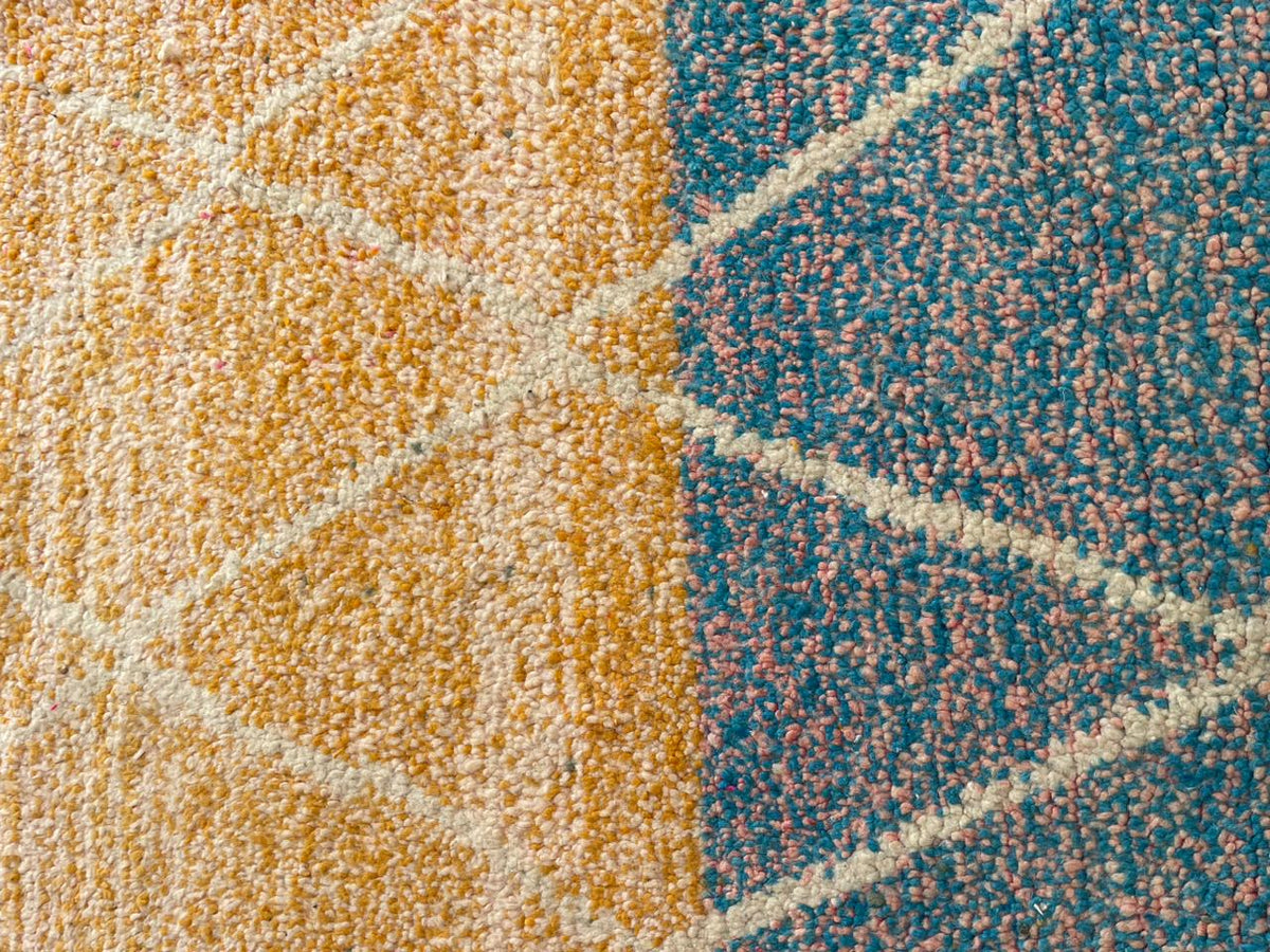 Detail view of a colorful Moroccan rug featuring a geometric pattern in blue and orange.