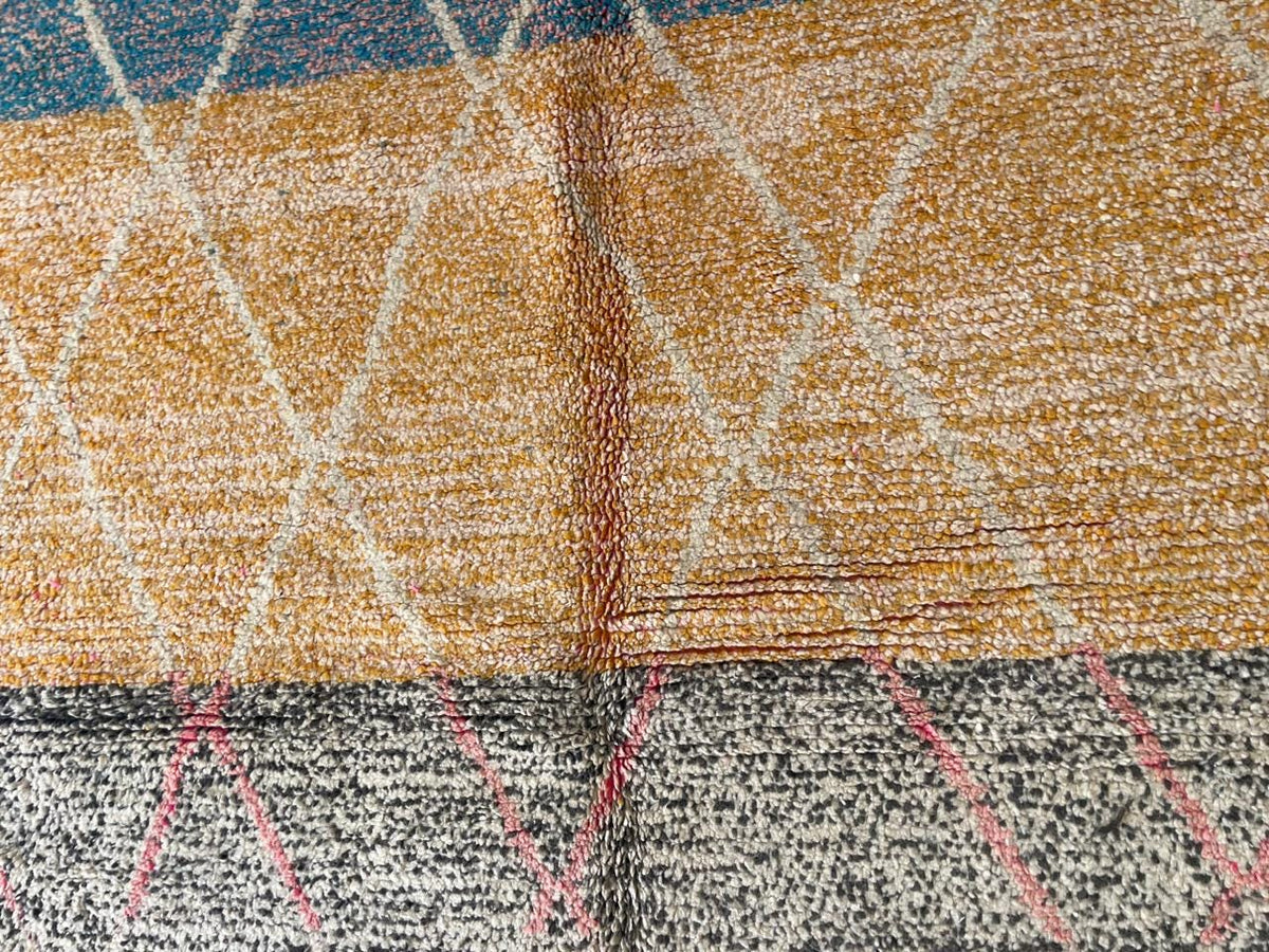 Close-up of the rug showing detailed stitching and geometric lines in blue, gold, and white.