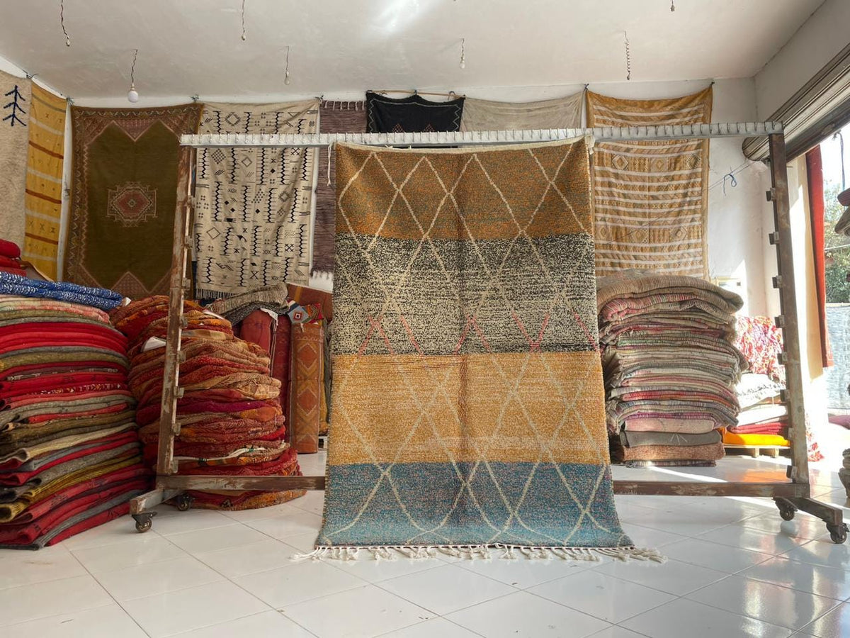 Lifestyle shot featuring a variety of colorful Moroccan rugs with different patterns in red, brown, and blue.
