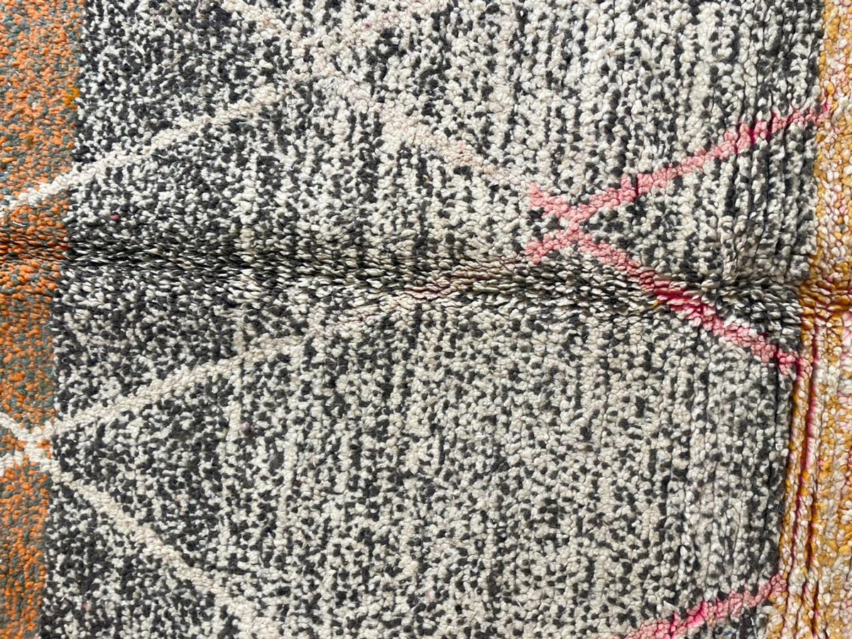 Close-up of a colorful Moroccan rug showcasing a geometric pattern in black and orange.