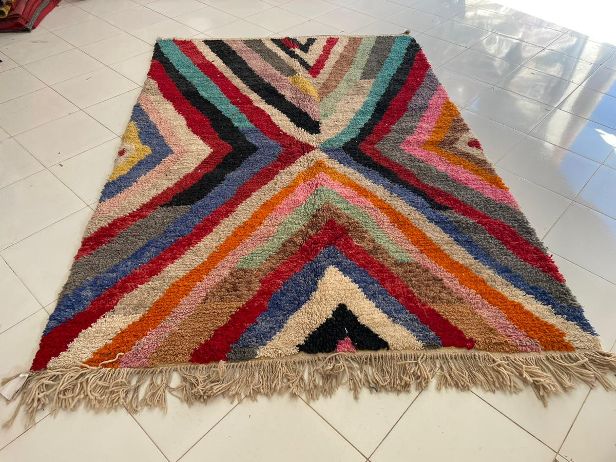 Front view of a colorful Moroccan rug with a zigzag design in red, blue, orange, and cream.