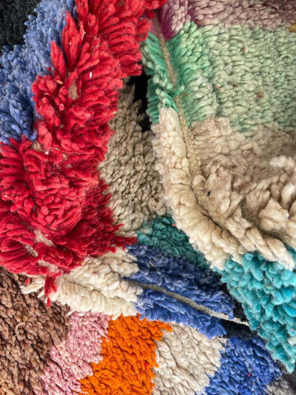 Detail shot of a colorful rug with a striped pattern in turquoise, brown, pink, and grey.