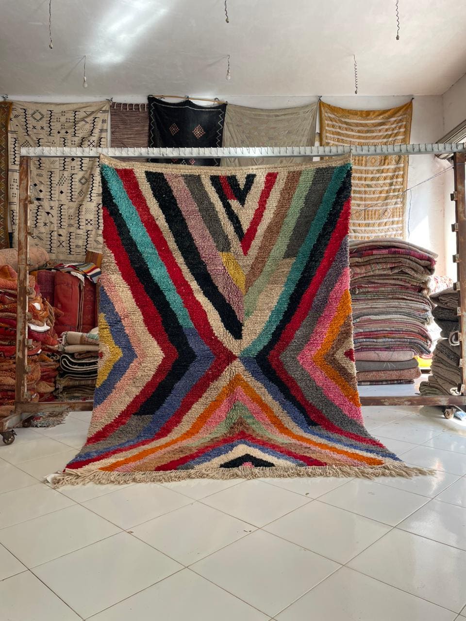 Lifestyle shot of a colorful Moroccan rug featuring geometric patterns in red, blue, yellow, and black.