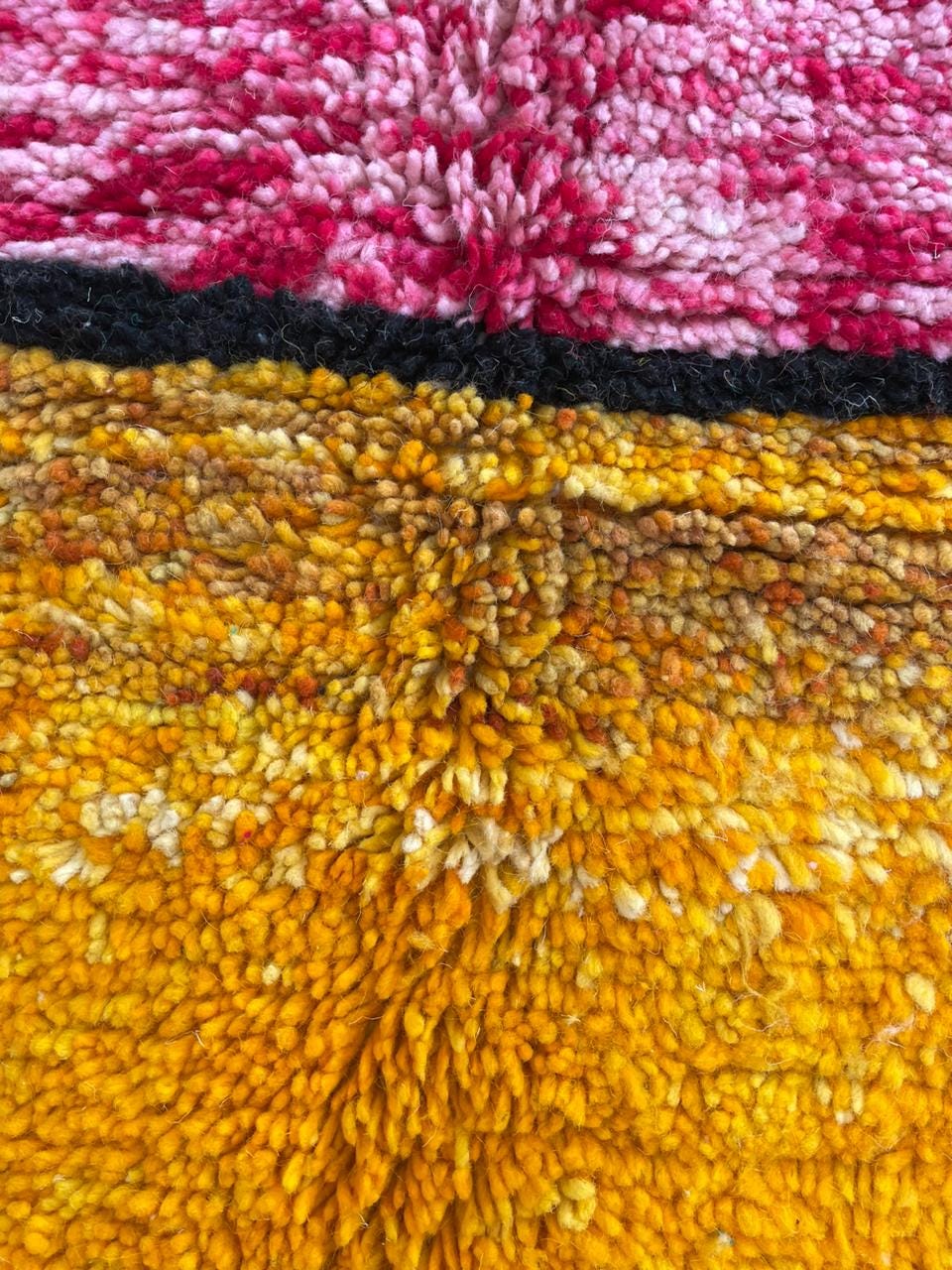 Detail close-up of a colorful rug with vibrant colors and a textured surface.