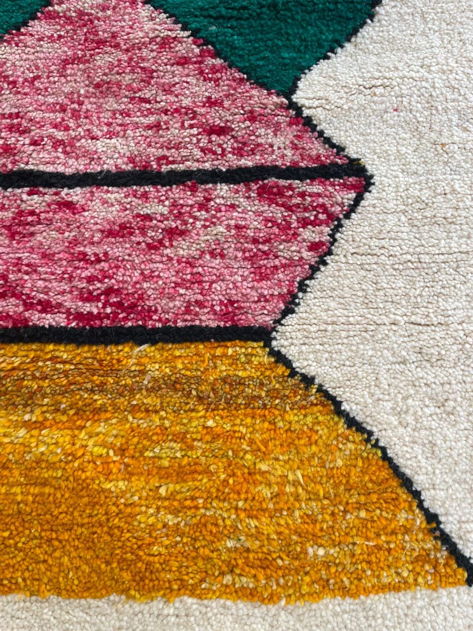 Detail close-up of a colorful rug featuring geometric patterns and a handmade texture.