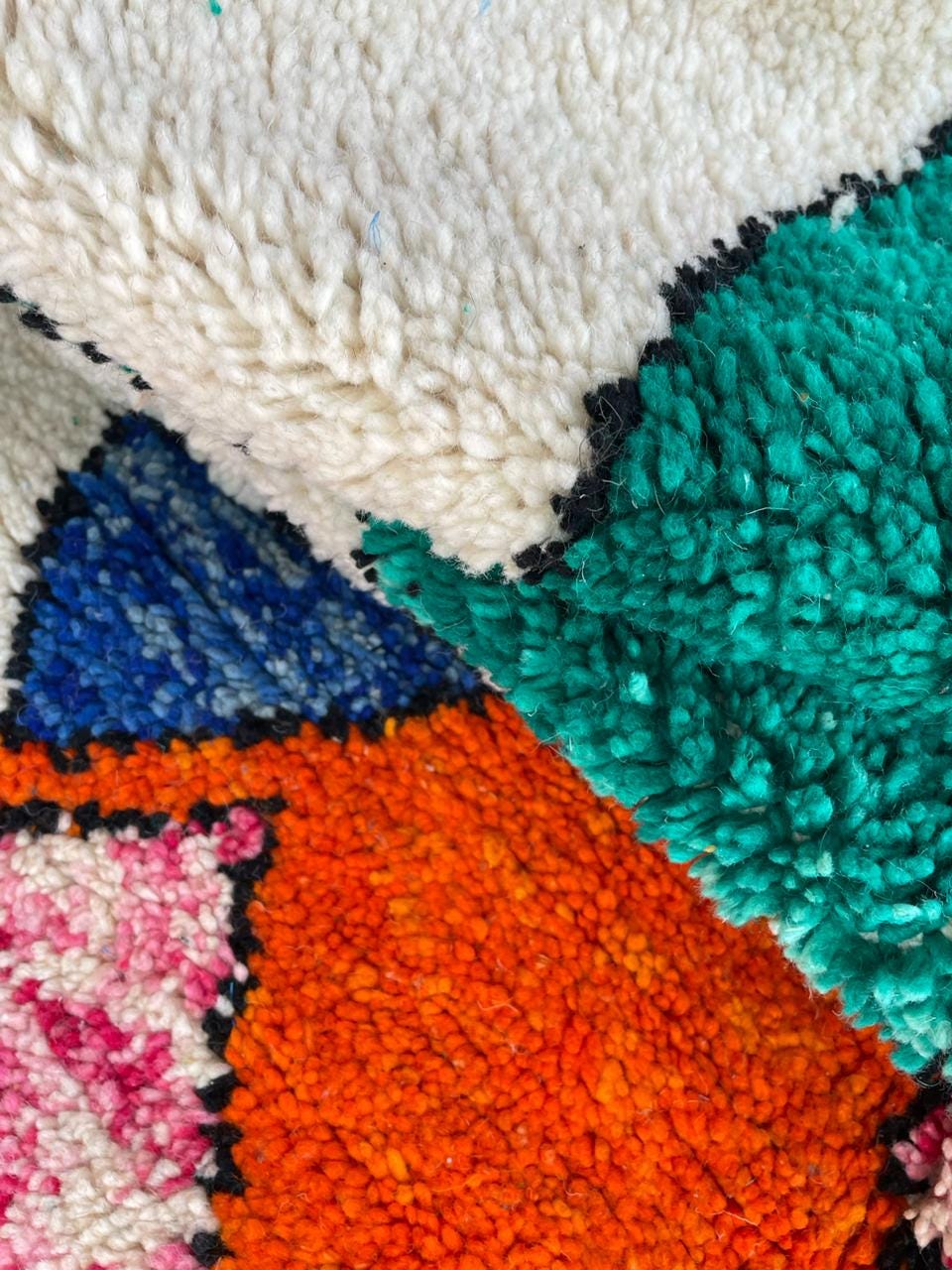 Detail close-up of a colorful rug with a textured surface and varied colors.