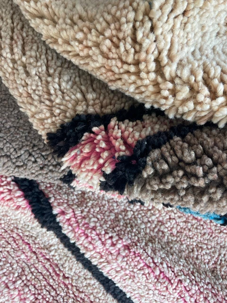 Close-up detail of a Moroccan rug showcasing layered texture and striped elements in beige, black, and red.