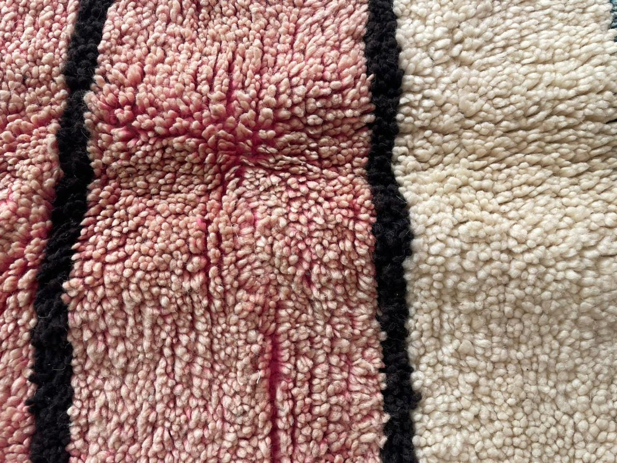 Close-up detail of a Moroccan rug with a striped pattern in cream, red, and black.