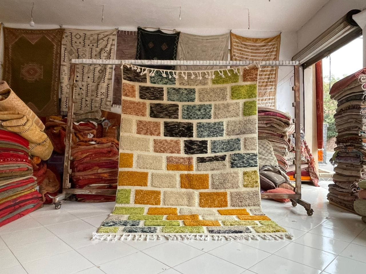 Lifestyle shot of a colorful Moroccan rug with orange, yellow, and green patterns in a natural setting.