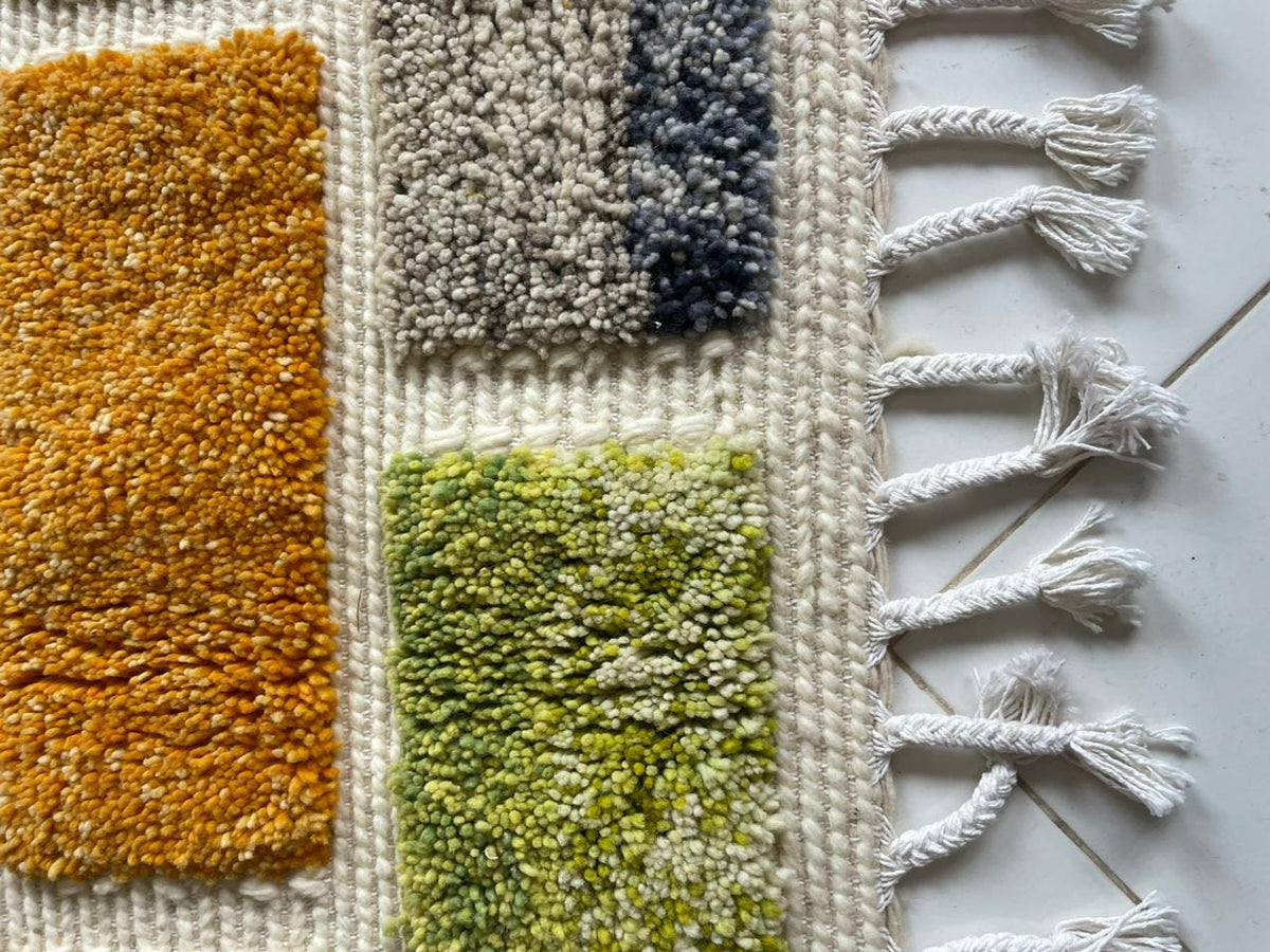 Detail shot of a colorful Moroccan rug with thick pile and vibrant color blocks in gray and orange.