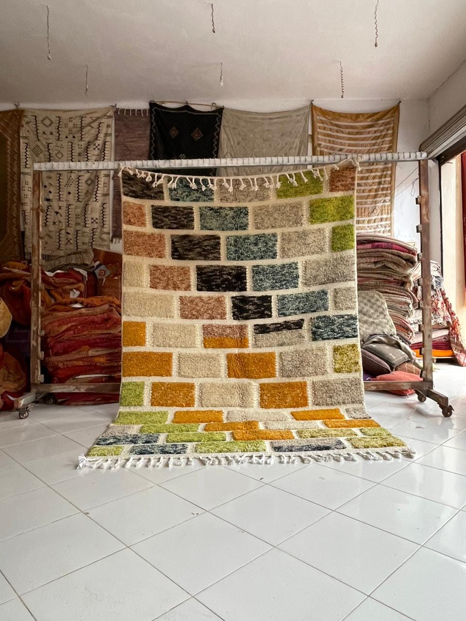 Lifestyle shot of a colorful Moroccan rug featuring orange, green, and blue hues in a natural setting.