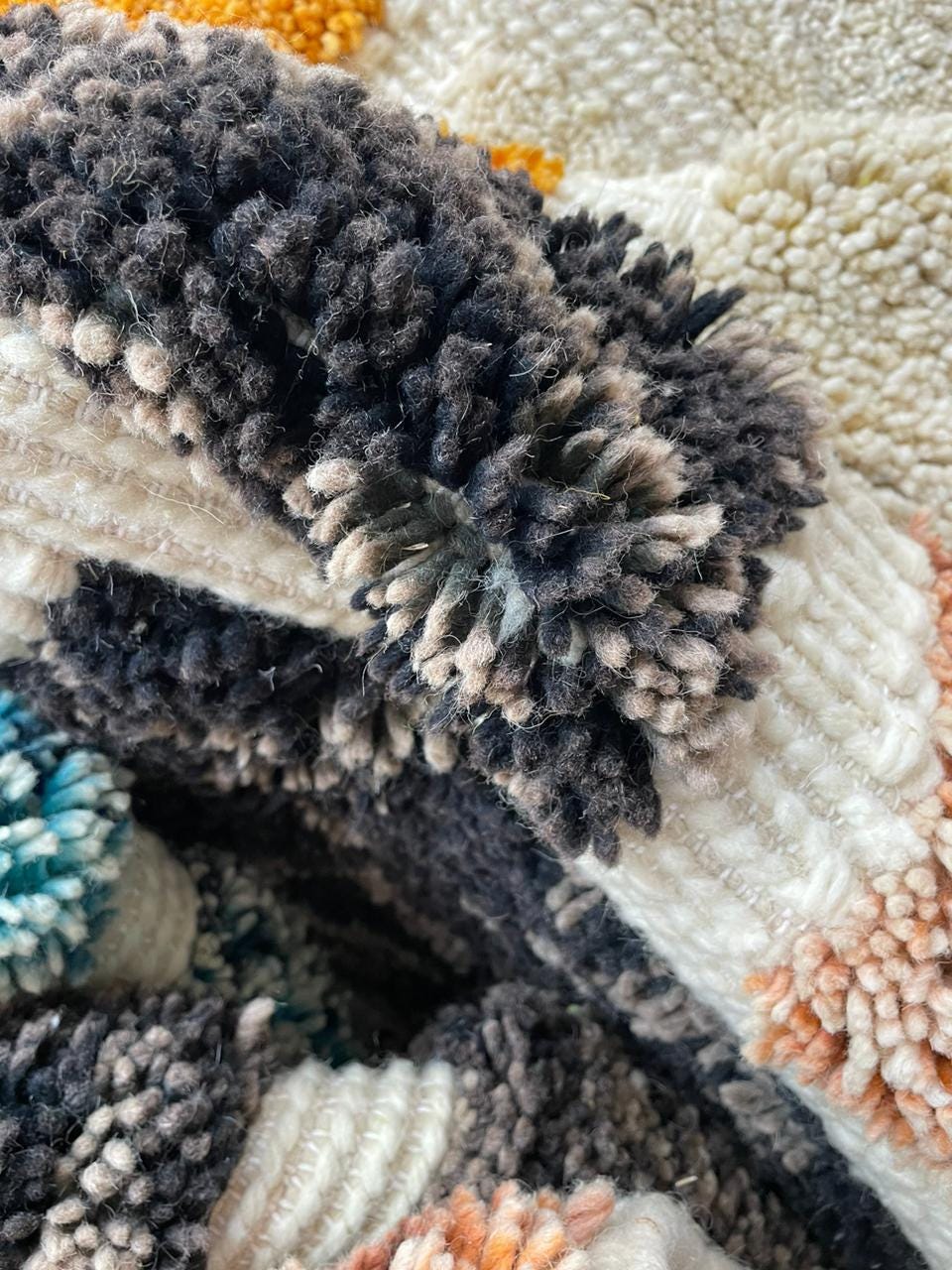 Close-up of a Moroccan rug showing intricate patterns in black, white, and orange.