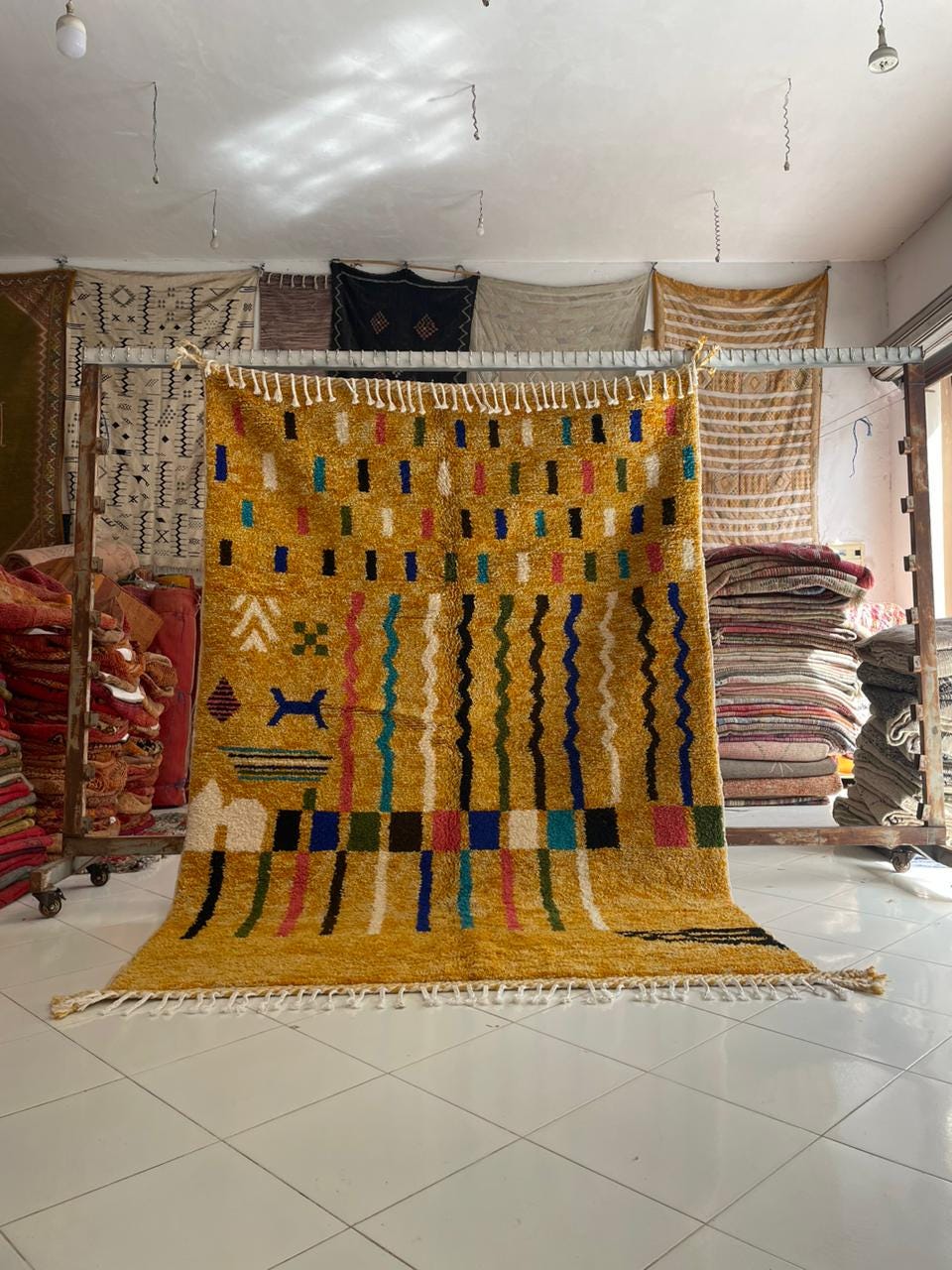 Lifestyle shot of a colorful Moroccan rug featuring geometric patterns in yellow, blue, pink, and black.