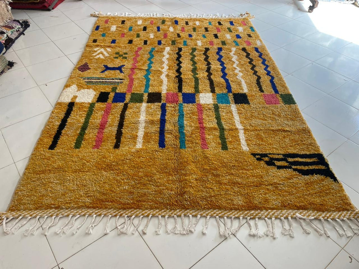 Top view of a colorful Moroccan rug showcasing geometric patterns in yellow, blue, pink, and black.