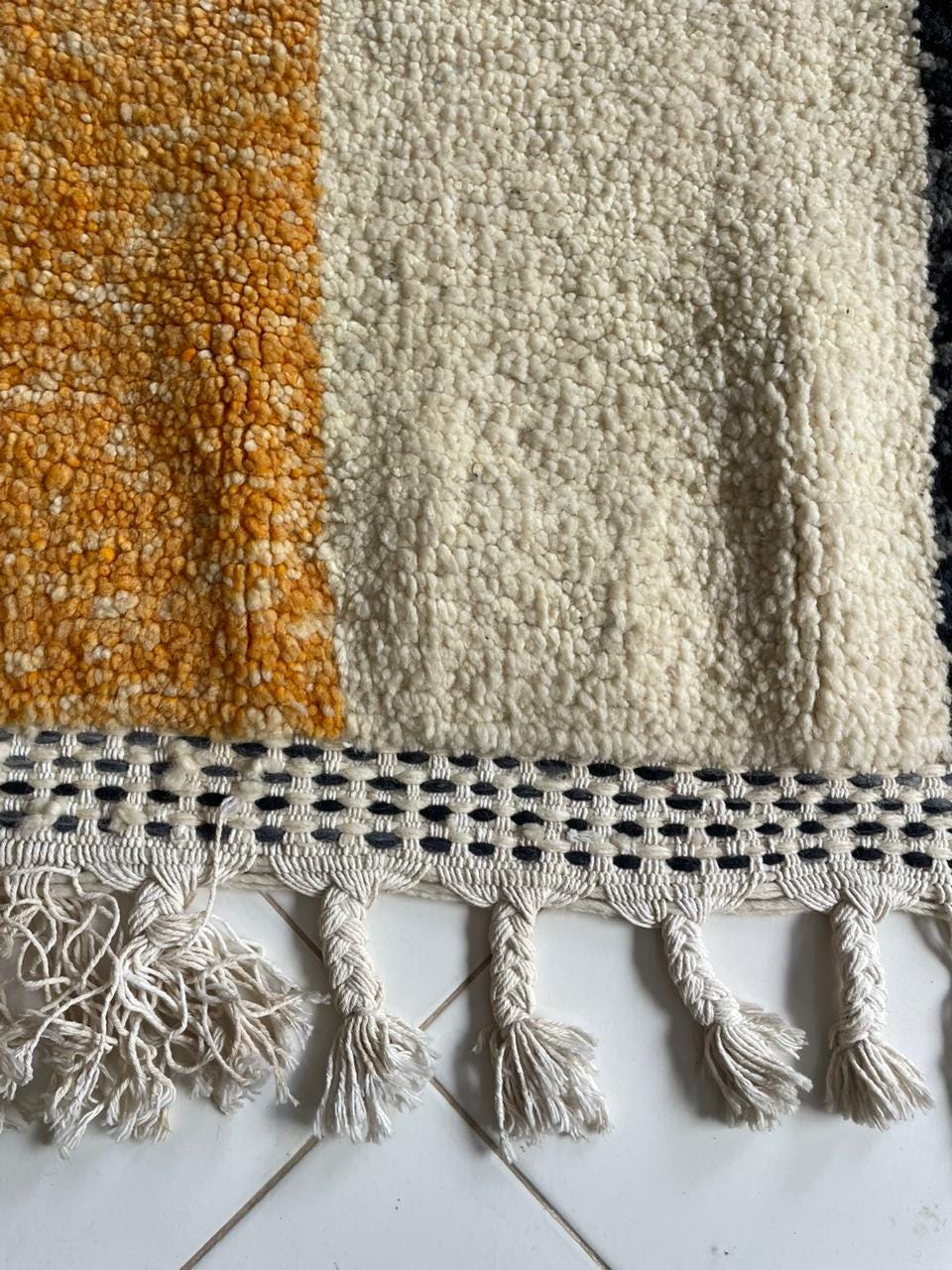 Close-up detail of a colorful Moroccan rug with fringe edges and textured surface.